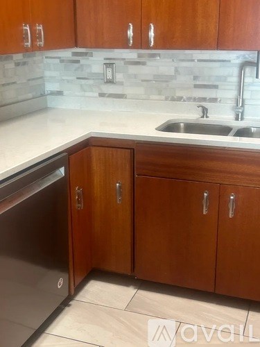 A kitchen with wooden cabinets and a marble backsplash.