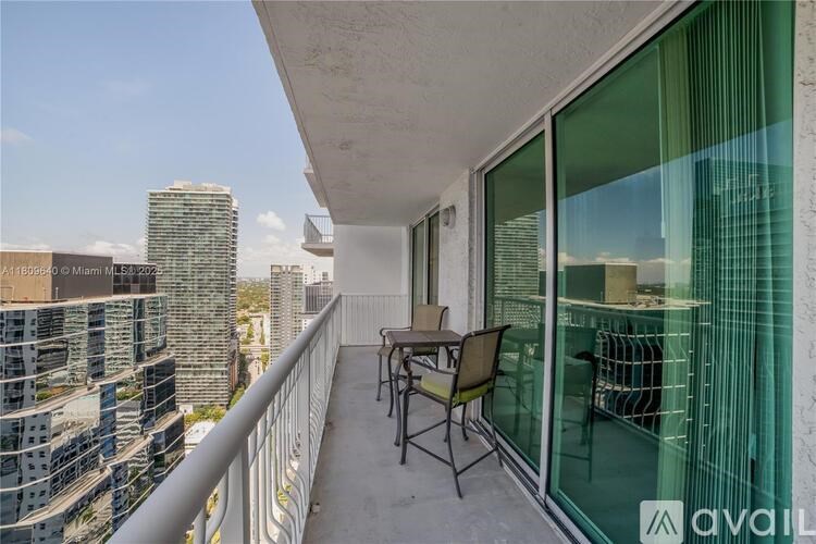 A balcony with a table and chairs overlooking a cityscape.