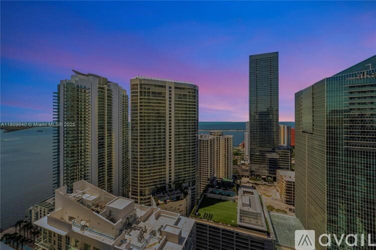 A cityscape with tall buildings and a body of water in the foreground.