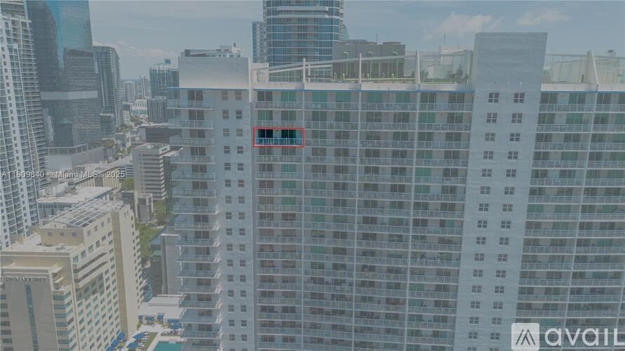 A tall building with many windows is in the foreground of a cityscape.