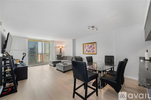 A living room with a glass table and black chairs.