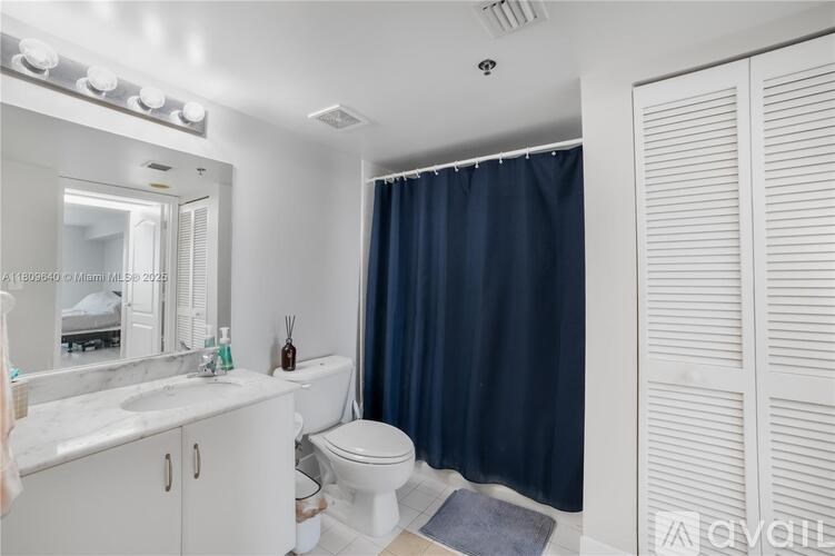 A bathroom with a white vanity, a toilet, and a shower curtain.