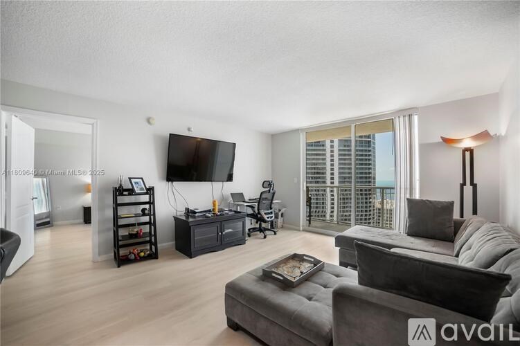 A living room with a grey couch and a flat screen TV mounted on the wall.