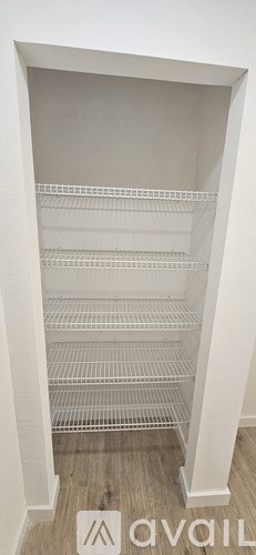 A white pantry with shelves and a wooden floor.