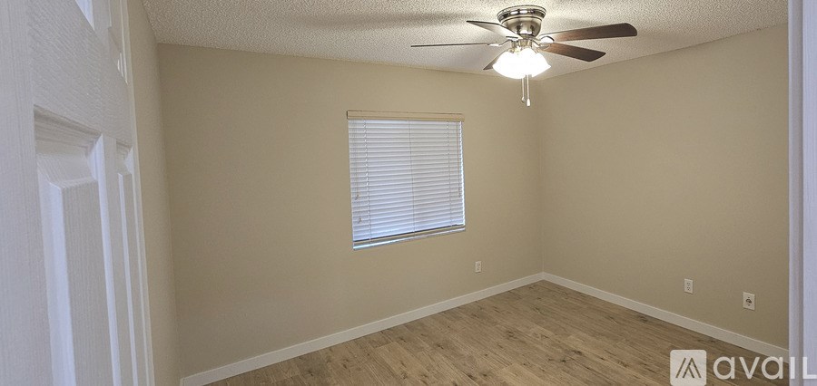 A room with a ceiling fan and a window with blinds.