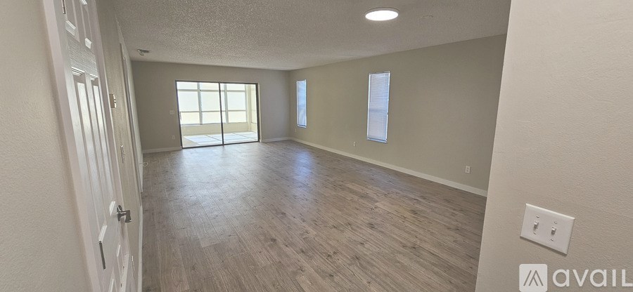 A spacious room with wooden flooring and a door leading to a balcony.