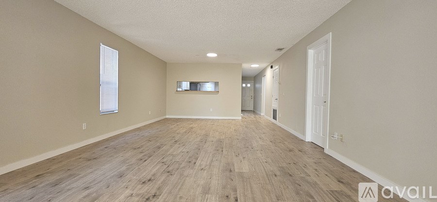 A spacious room with wooden flooring and white walls.