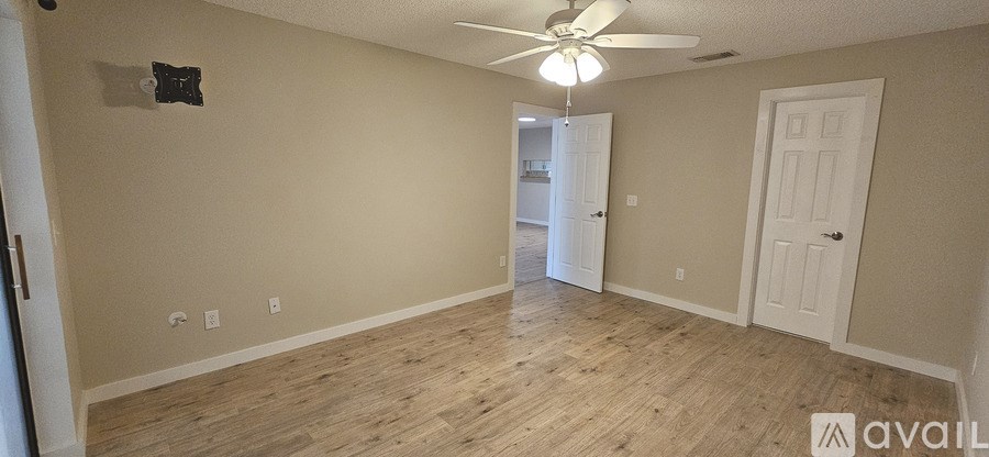 A room with a ceiling fan and wooden flooring.