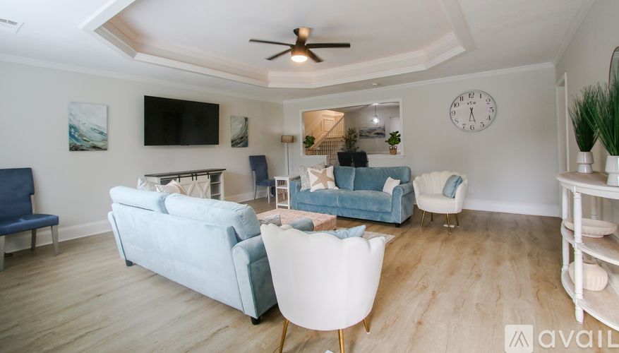 A living room with a white ceiling fan and a television on the wall.