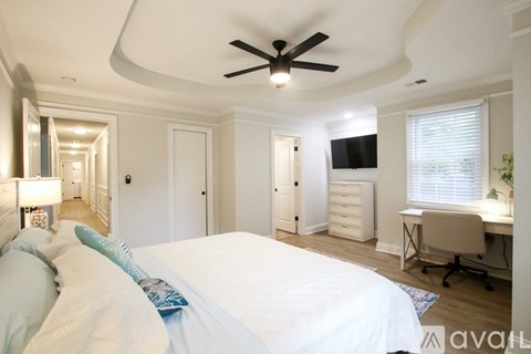 A bedroom with a large bed and a ceiling fan.