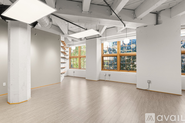 A spacious room with wooden floors and large windows.