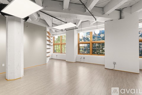 A spacious room with wooden floors and large windows.