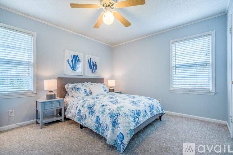 A bedroom with a bed, two lamps, and two framed pictures on the wall.