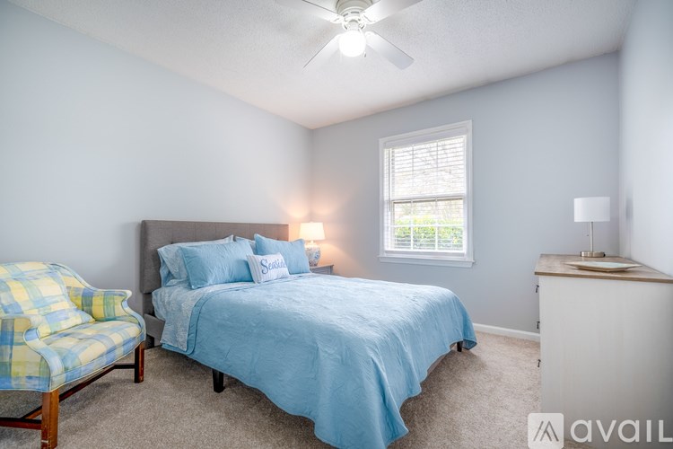 A bedroom with a bed, chair, and window.