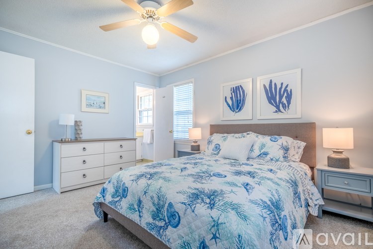A bedroom with a bed, dresser, and ceiling fan.
