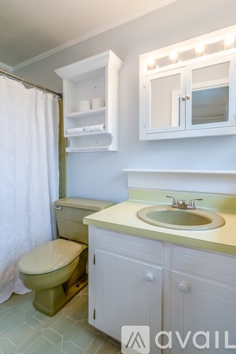 A bathroom with a toilet, sink, and cabinet.