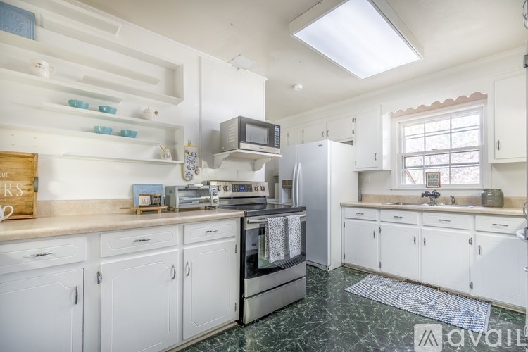 A kitchen with white cabinets and a green floor.