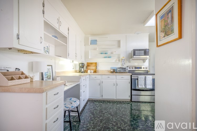 A kitchen with white cabinets and a marble floor.