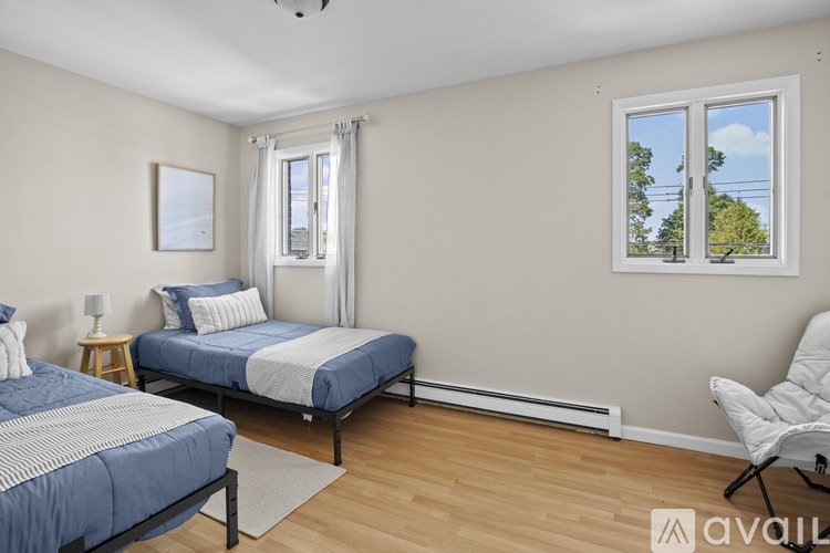 A bedroom with two beds and a window showing trees and sky.