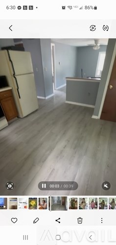 A white refrigerator is in a kitchen with light wood flooring.