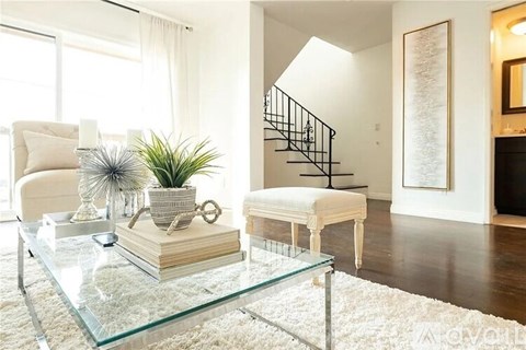 A living room with a glass coffee table and a white chair.