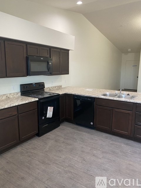 A kitchen with brown cabinets and black appliances.