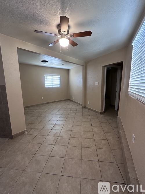 A room with a ceiling fan and a window with blinds.