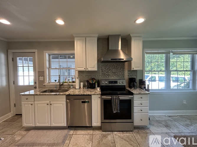 A kitchen with white cabinets and a marble countertop.