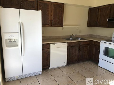 A kitchen with white appliances and brown cabinets.