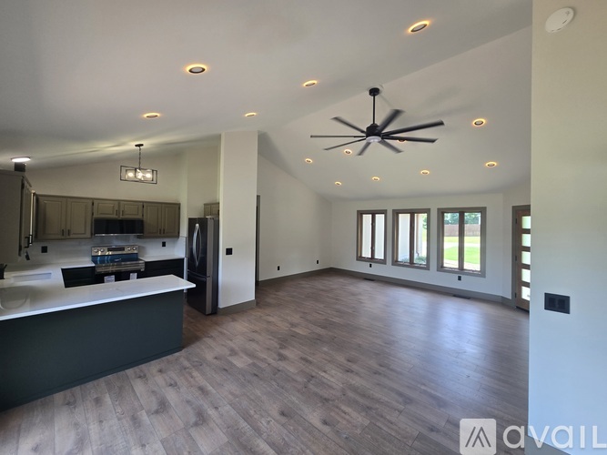 A spacious room with a ceiling fan and wooden flooring.