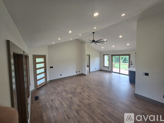 A spacious room with wooden flooring and a ceiling fan.