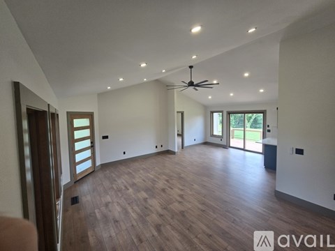 A spacious room with wooden flooring and a ceiling fan.