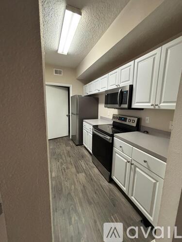 A kitchen with white cabinets and a black microwave.