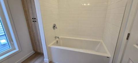 A white bathtub in a bathroom with white tiles.