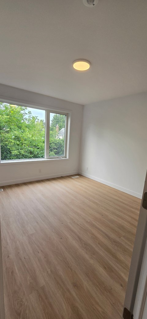 A room with a window and wooden flooring.