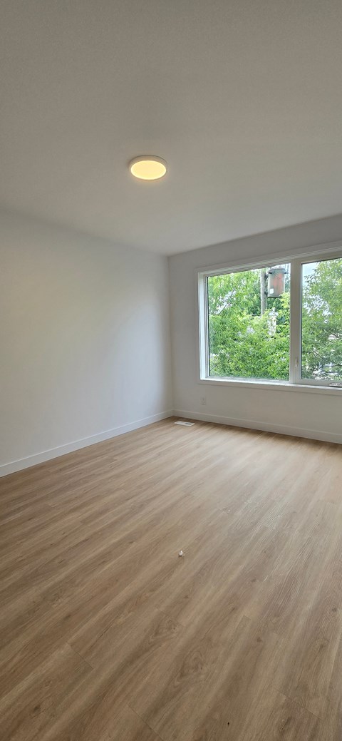 A room with a window and wooden flooring.