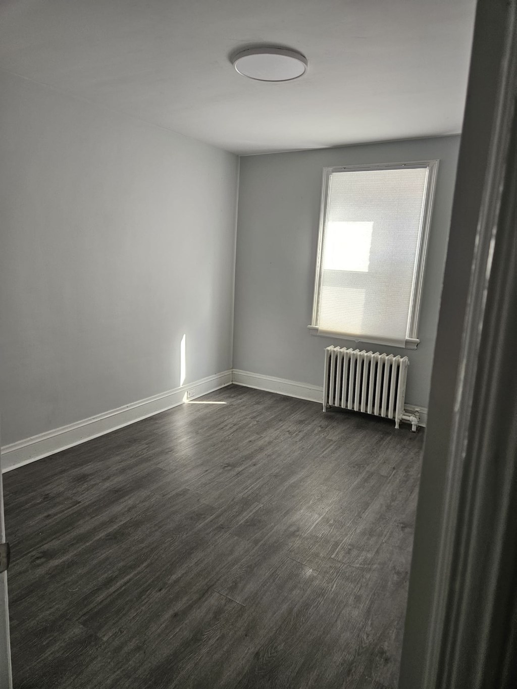 A room with a window and a radiator on the floor.