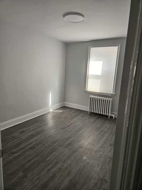 A room with a window and a radiator on the floor.
