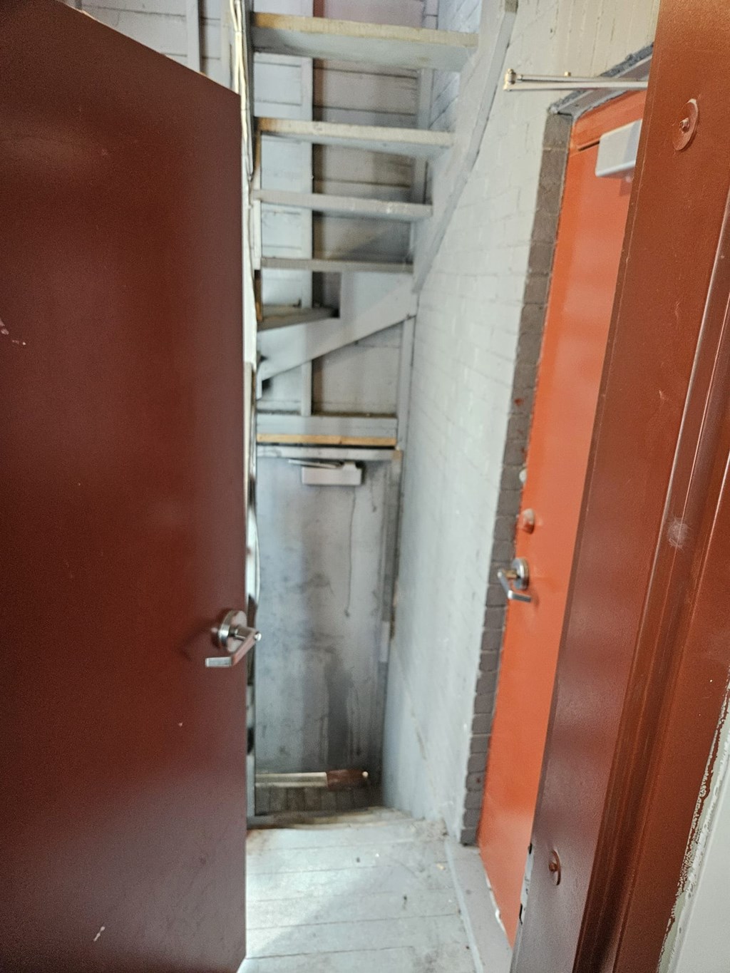 A red door is open to a stairwell.