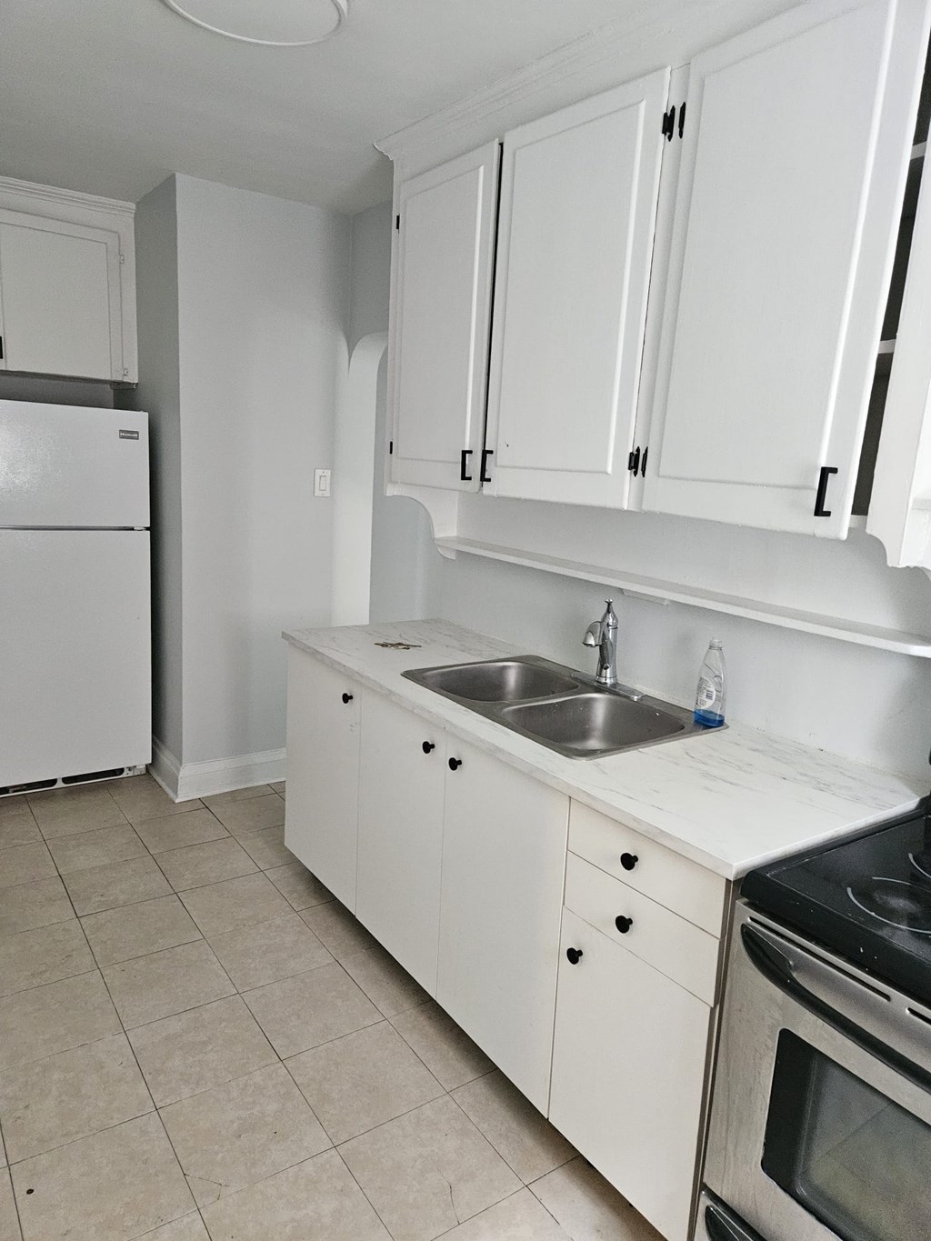 A kitchen with white cabinets and a white fridge.