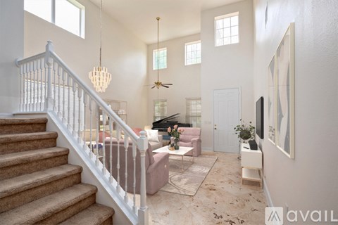 A living room with a staircase and a ceiling fan.