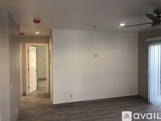 A spacious room with a ceiling fan and a doorway leading to another room.