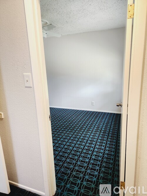 A room with a carpeted floor and a doorway leading to another room.