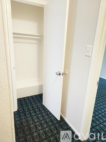 A hallway with a carpeted floor and white walls.