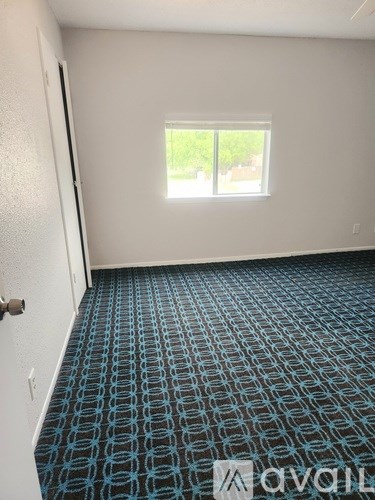 A room with a carpeted floor and a window.