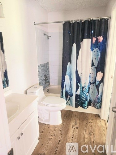 A bathroom with a toilet, sink, and shower curtain.