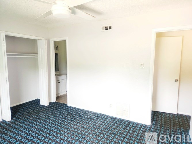 A room with a ceiling fan and a patterned carpet.