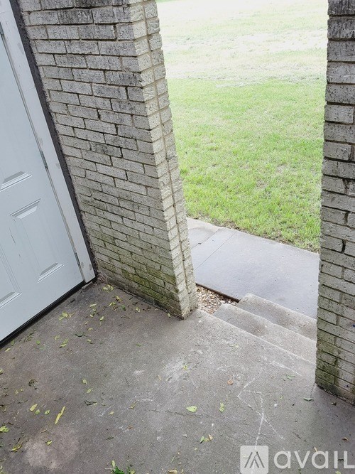 A white door is attached to a brick wall.