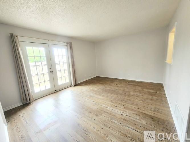 A room with wooden flooring and a sliding glass door.