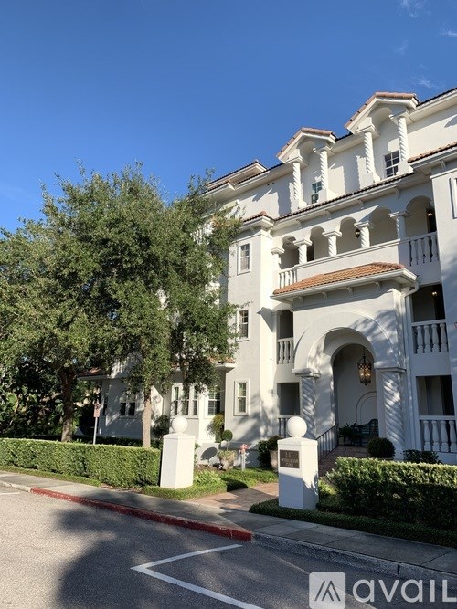 A white building with a balcony and a tree in front of it.